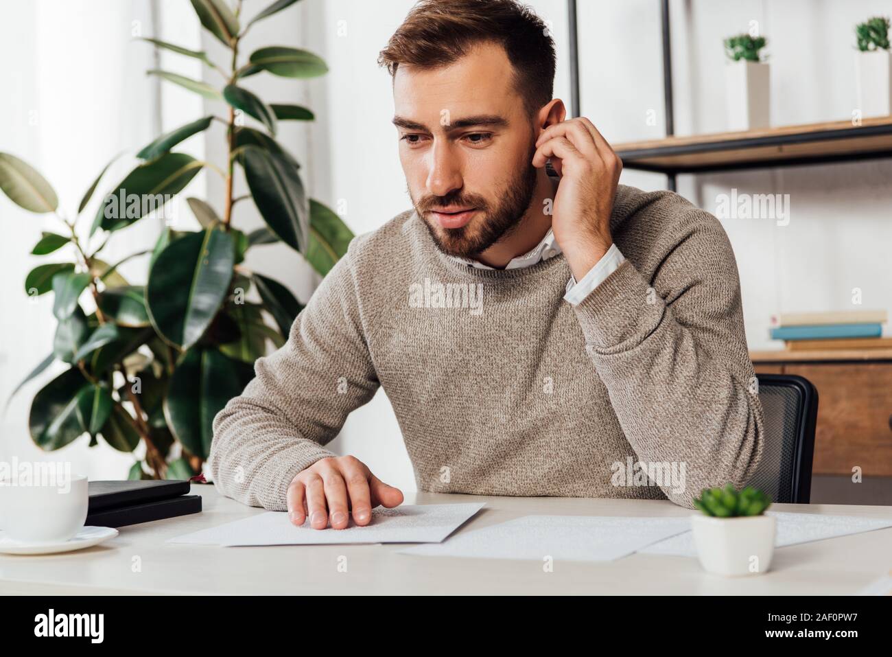 Blind man using wireless earphones while reading at table Stock Photo
