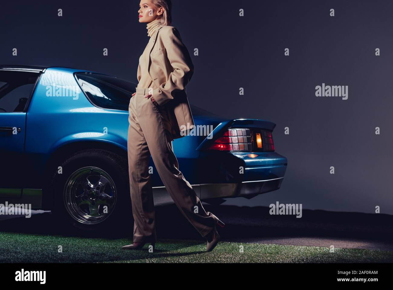 attractive and stylish woman in suit walking near retro car Stock Photo