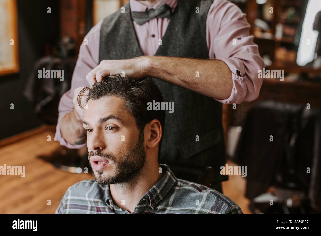barber styling hair on handsome bearded man Stock Photo