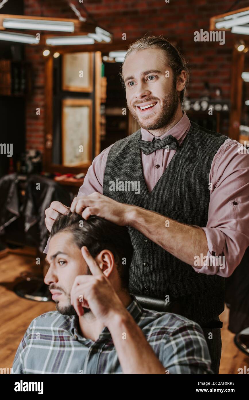 cheerful barber styling hair on handsome bearded man Stock Photo