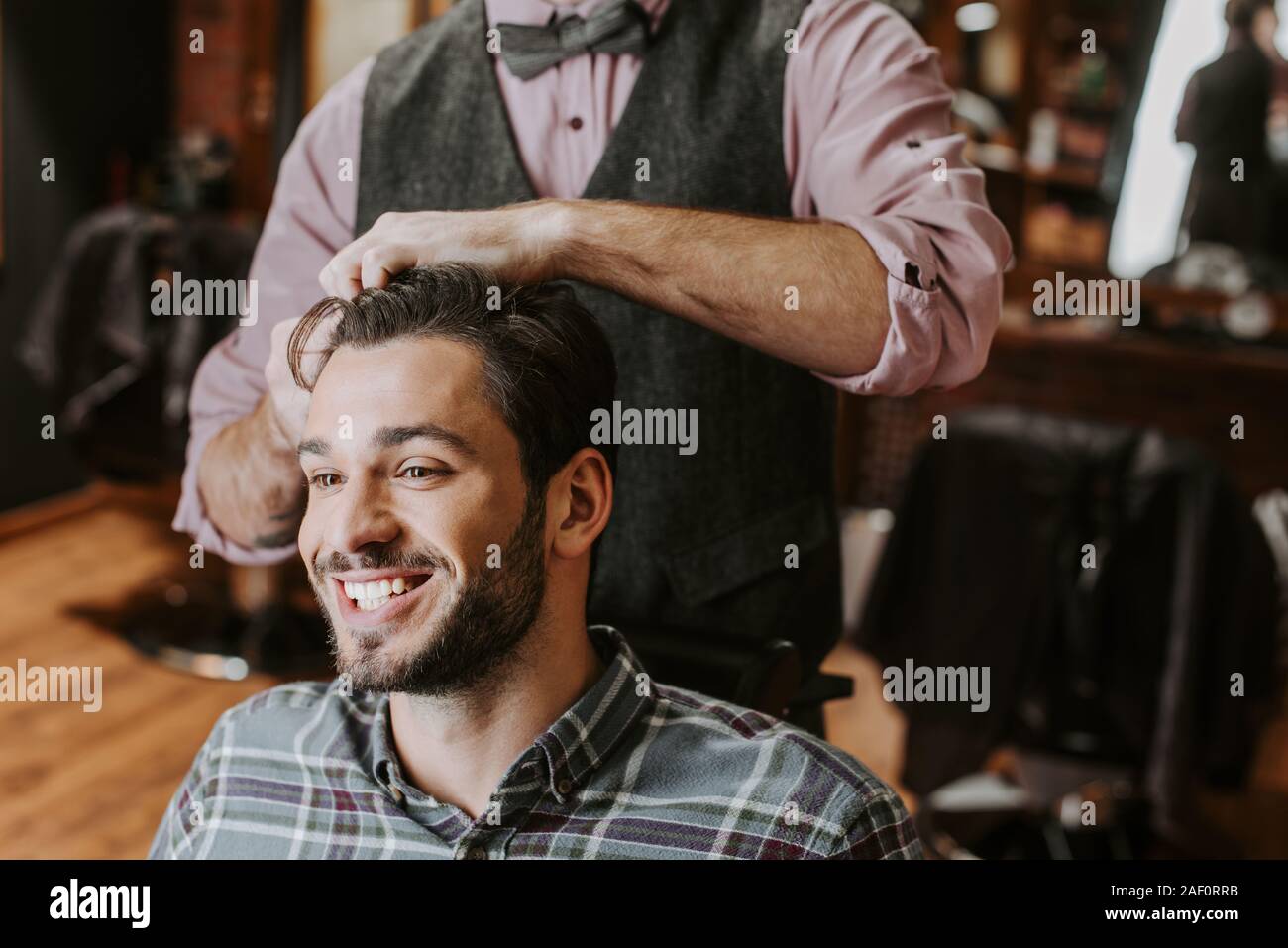 barber styling hair on cheerful bearded man Stock Photo