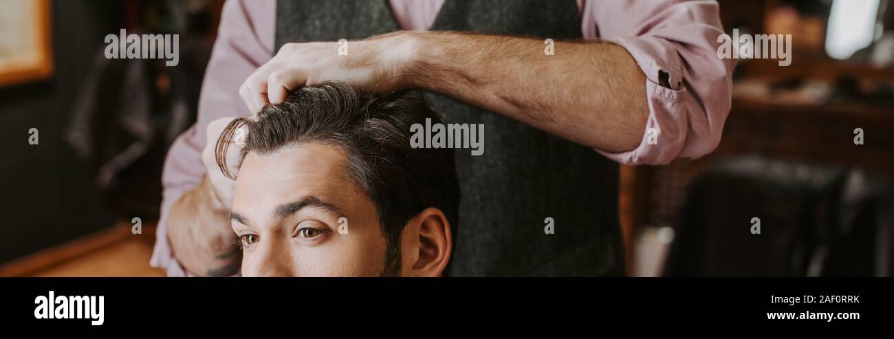 panoramic shot of barber styling hair on man Stock Photo