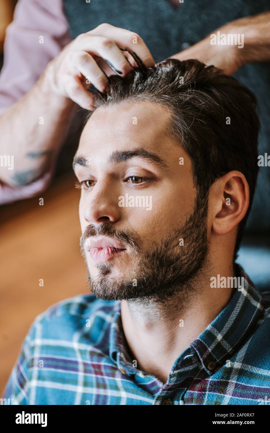 barber with black hair pomade on hands styling hair of handsome man Stock Photo