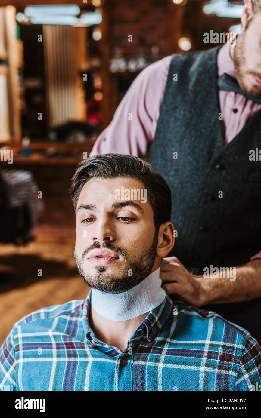 barber fixing collar around neck of handsome bearded man Stock Photo