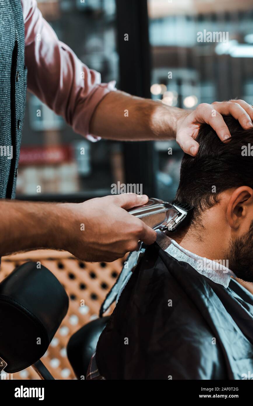 cropped view of barber styling hair of man in barbershop Stock Photo