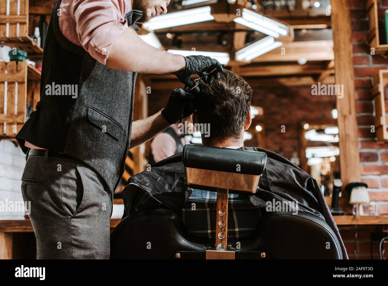 bearded barber cutting hair of man in barbershop Stock Photo
