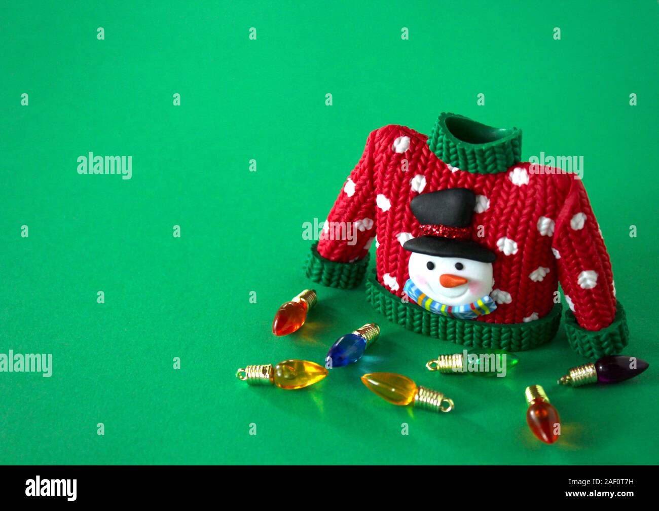 red sweater with green collar and sleeve cuffs white snowflakes and snowman with black hat and carrot nose isolated on a festive red background Stock Photo