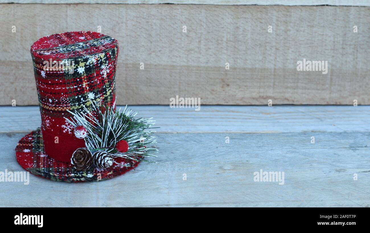Plaid red, green and white top hat with pine cones on pine branch on a wood background with copy space Stock Photo