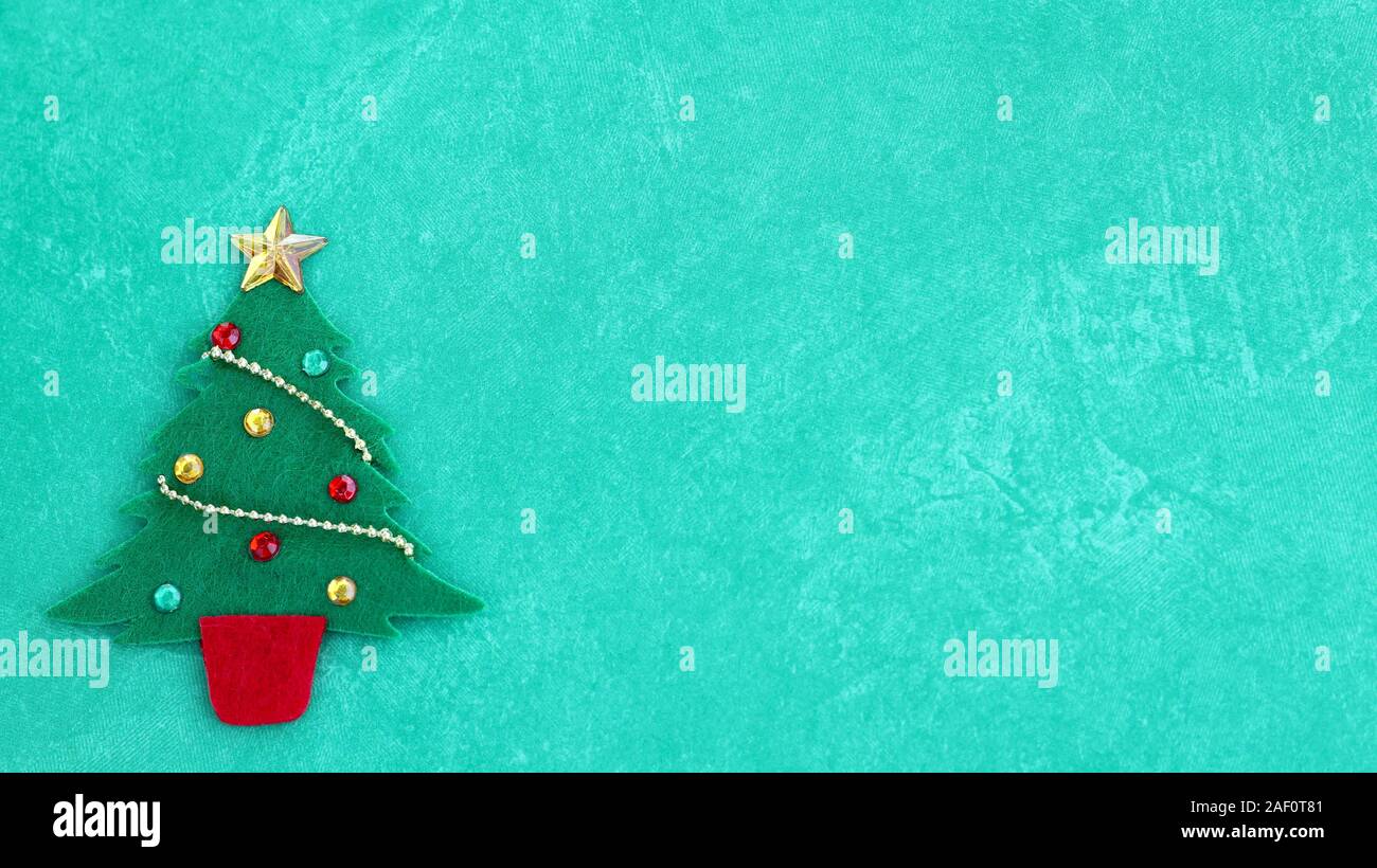 felt decorated craft christmas tree with gold star, garland on a festive green background Stock Photo