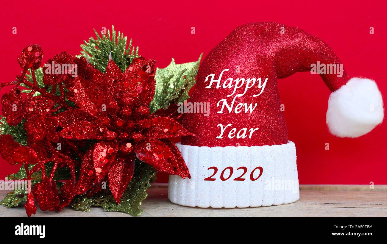 glittery red and white Santa hat and shiny red and green leaves with happy new year message 2020 Stock Photo