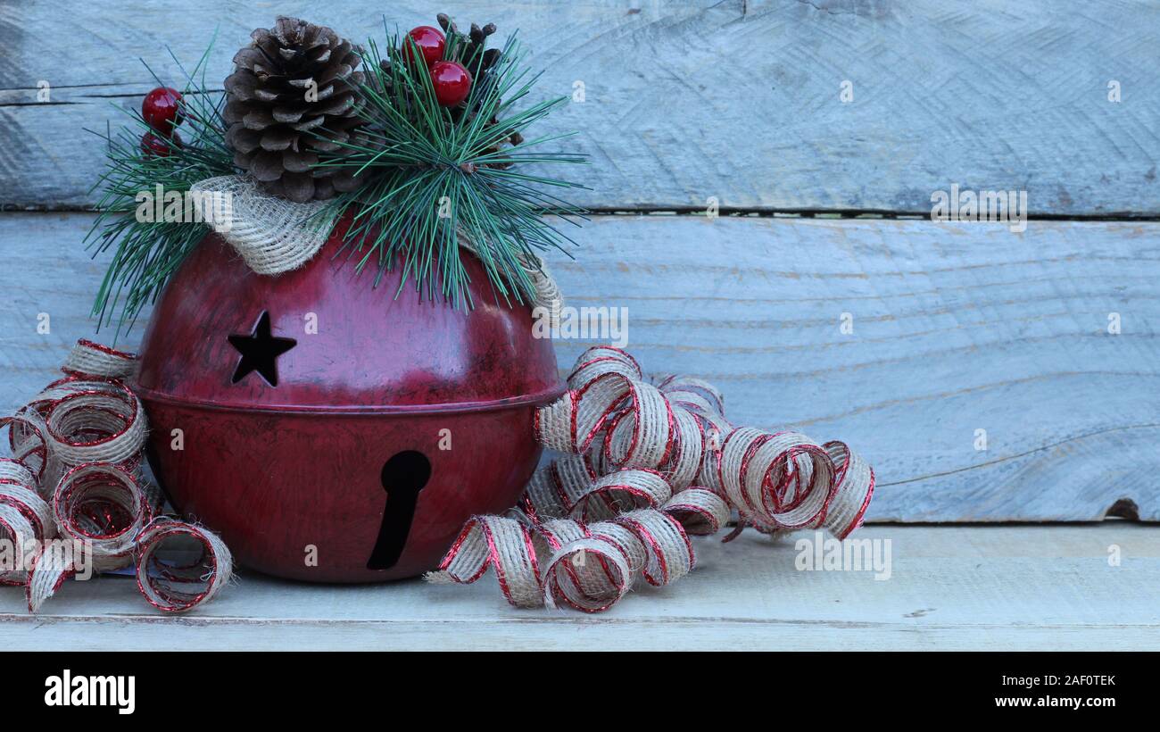 red rustic bell with pine cone and ribbons on a wood background with writing space Stock Photo