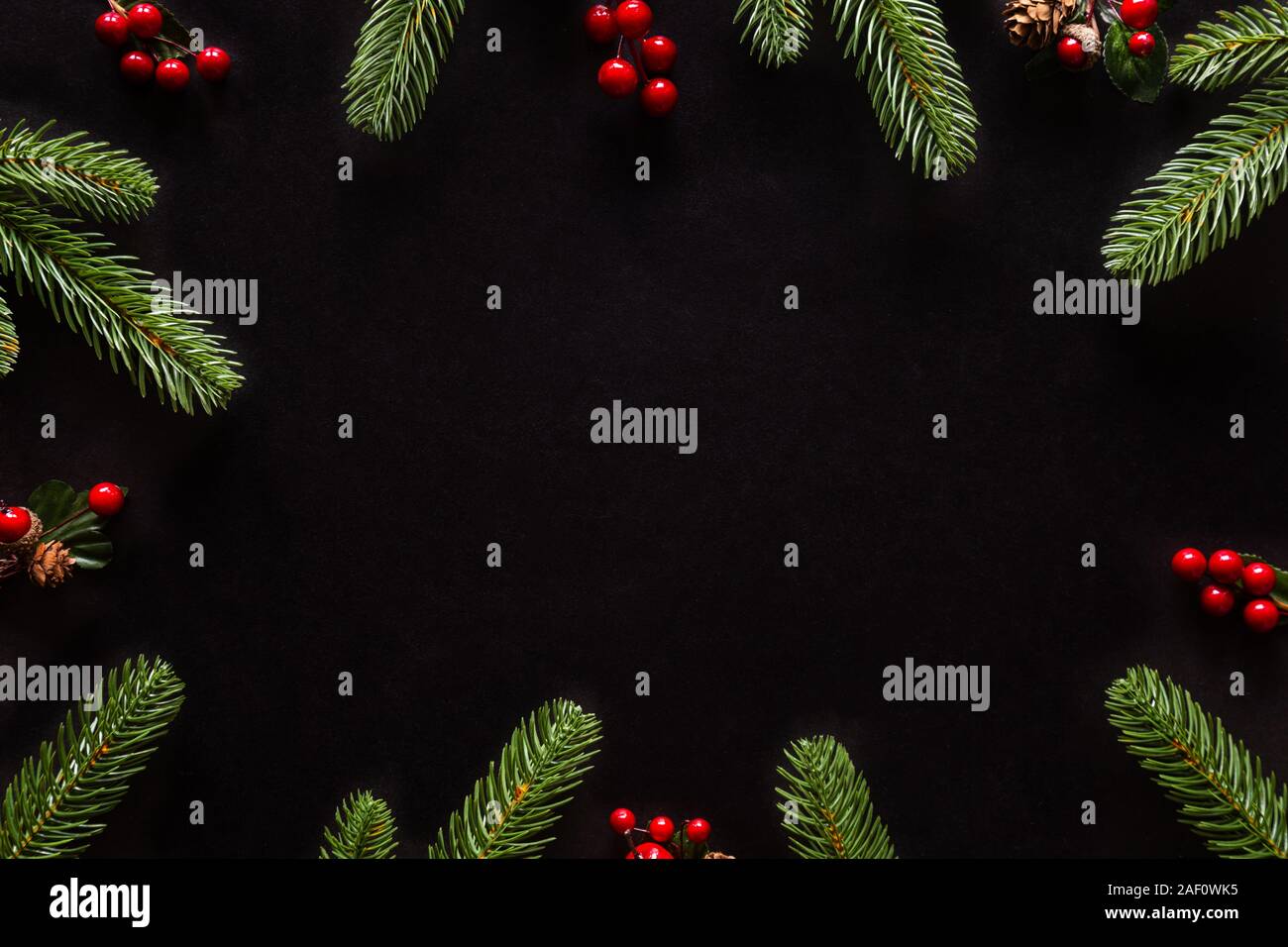 Holiday Christmas card background with festive decoration ball, stars, snowflakes, gift box, pine cones on a black background from Flat lay, top view. Stock Photo