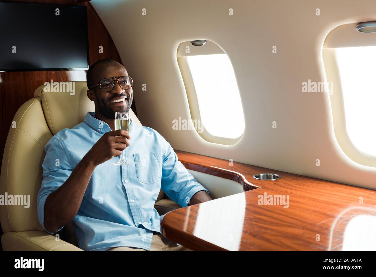 Afrikanische amerikanische Geschäftsmann mit schlafbrille sitzen in der  Nähe von Gadgets in privaten Flugzeug Stockfotografie - Alamy