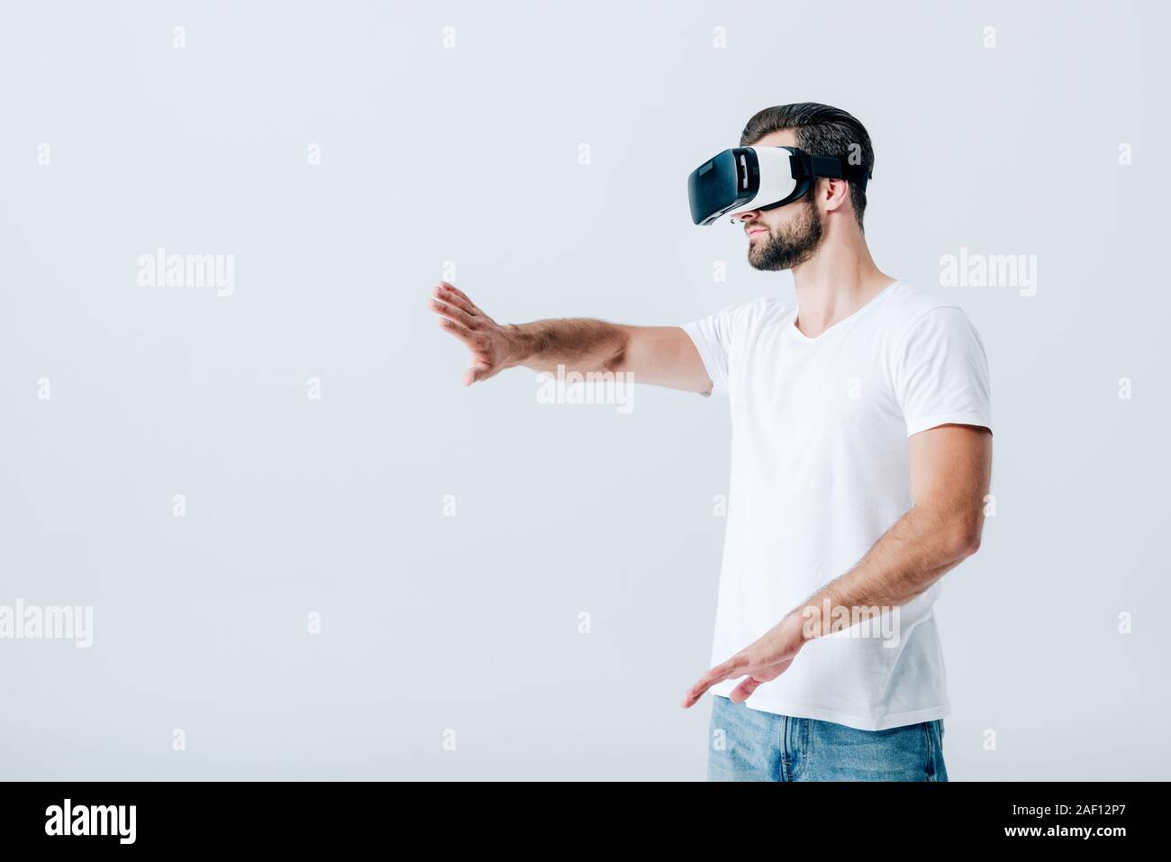 bearded man in Virtual reality headset gesturing isolated on grey Stock Photo