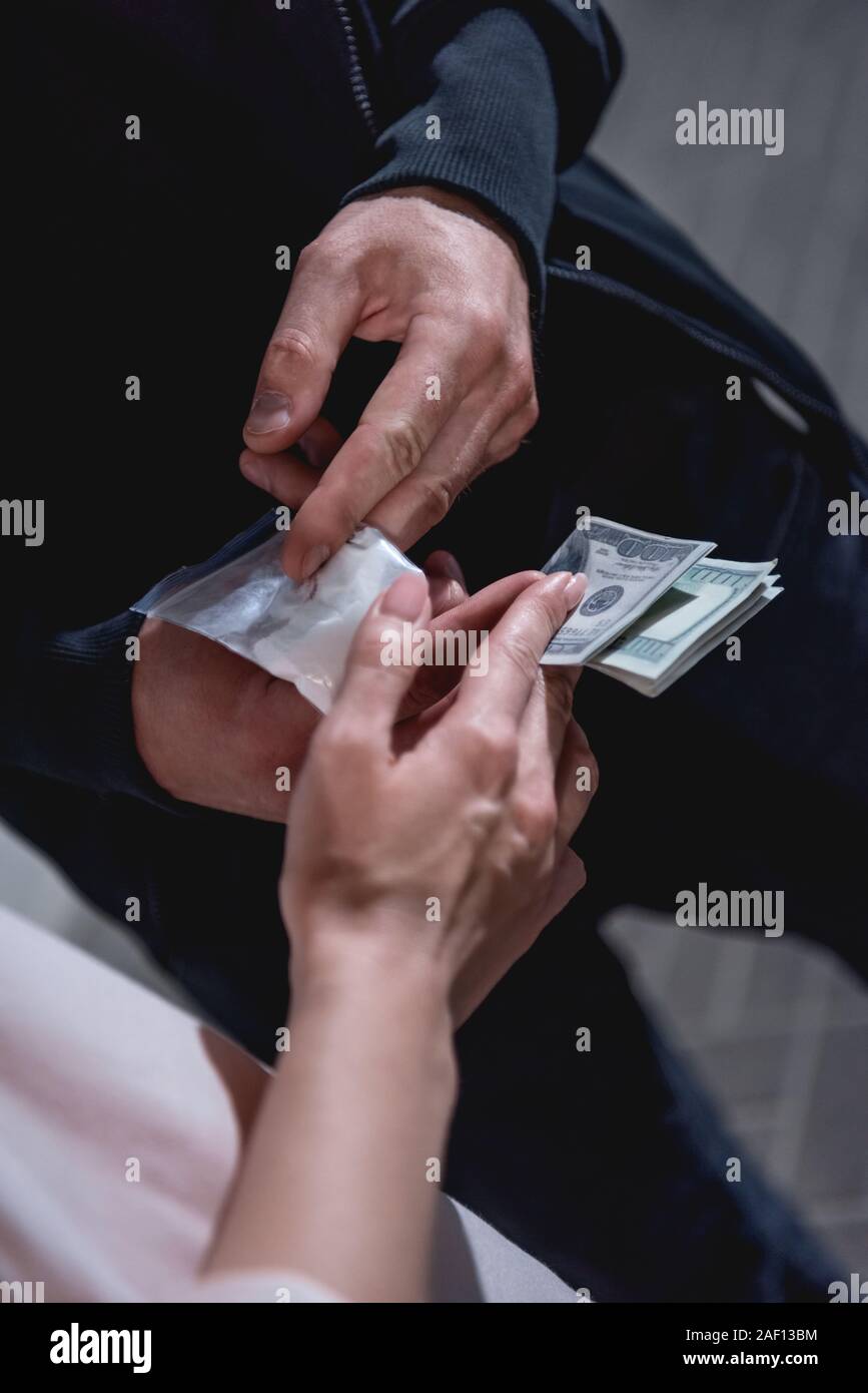 partial view of woman with dollar banknotes buying drugs from thug Stock Photo
