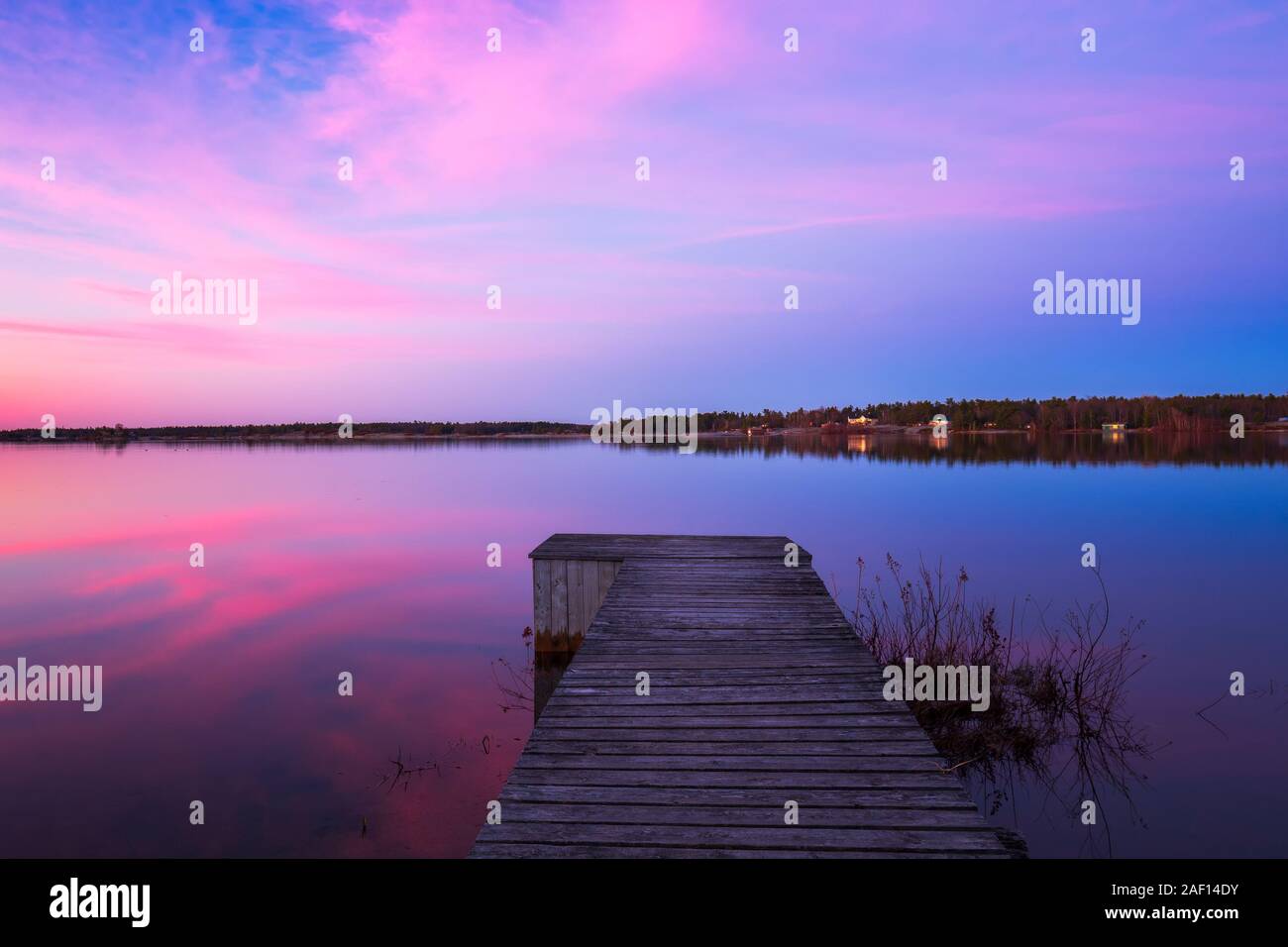 A Pink sunrise casts beautiful reflections on a still lake near Parry Sound in Northern Ontario, Canada on a Spring morning Stock Photo