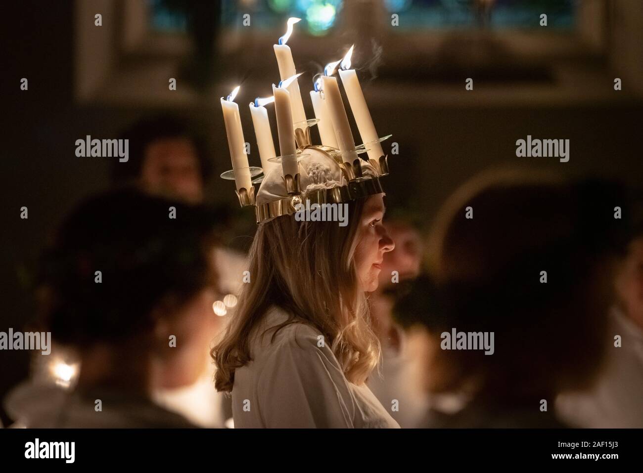 London, UK. 11th December, 2019. Liv Palmblad, from Sweden, playing the role of Lucia, leads the procession during the London Nordic Choir’s traditional Scandinavian ‘Sankta Lucia’ concert at St John’s Church near Hyde Park. The service features a candlelit procession of choristers led by a girl, Lucia, wearing a crown of candles and a red sash around her waist. Credit: Guy Corbishley/Alamy Live News Stock Photo