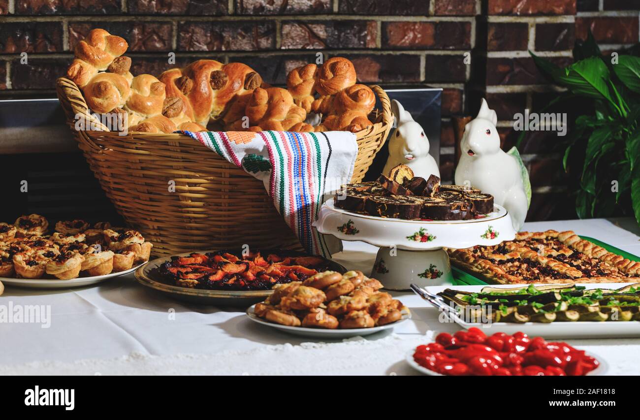 Easter holiday table with traditional bread and authentic Romanian food. Baked buns, colaci or cakes in straw baskets and towel with rustic motifs. Br Stock Photo