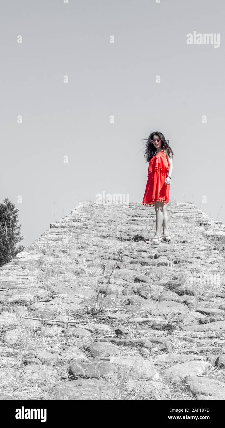 Girl in red dress standing on ancient bridge Stock Photo