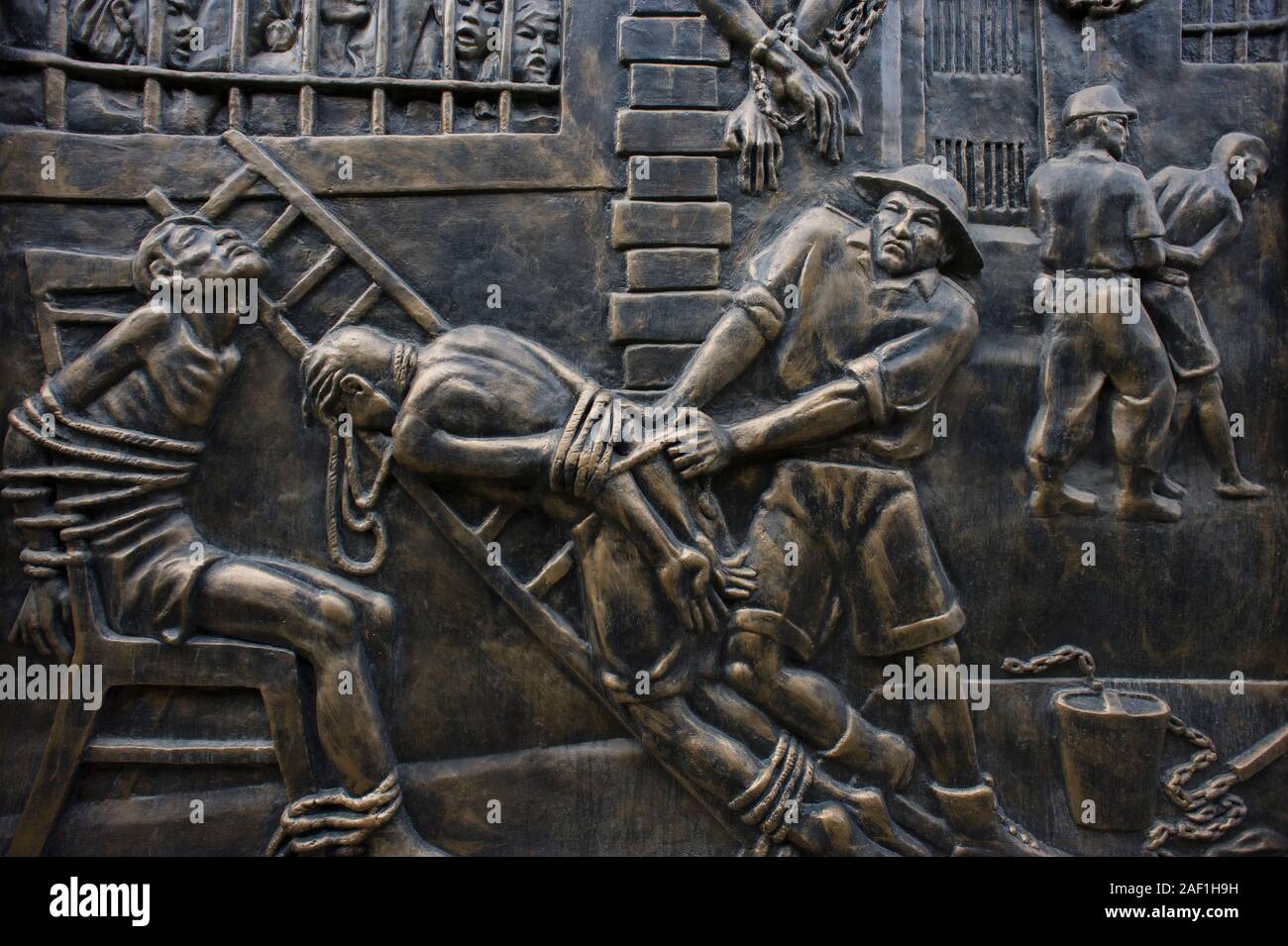 Hanoi, Vietnam - March 31, 2011: Sculpture in a bronze wall at Maison Centrale with the history of torture practice against war prisoners Stock Photo