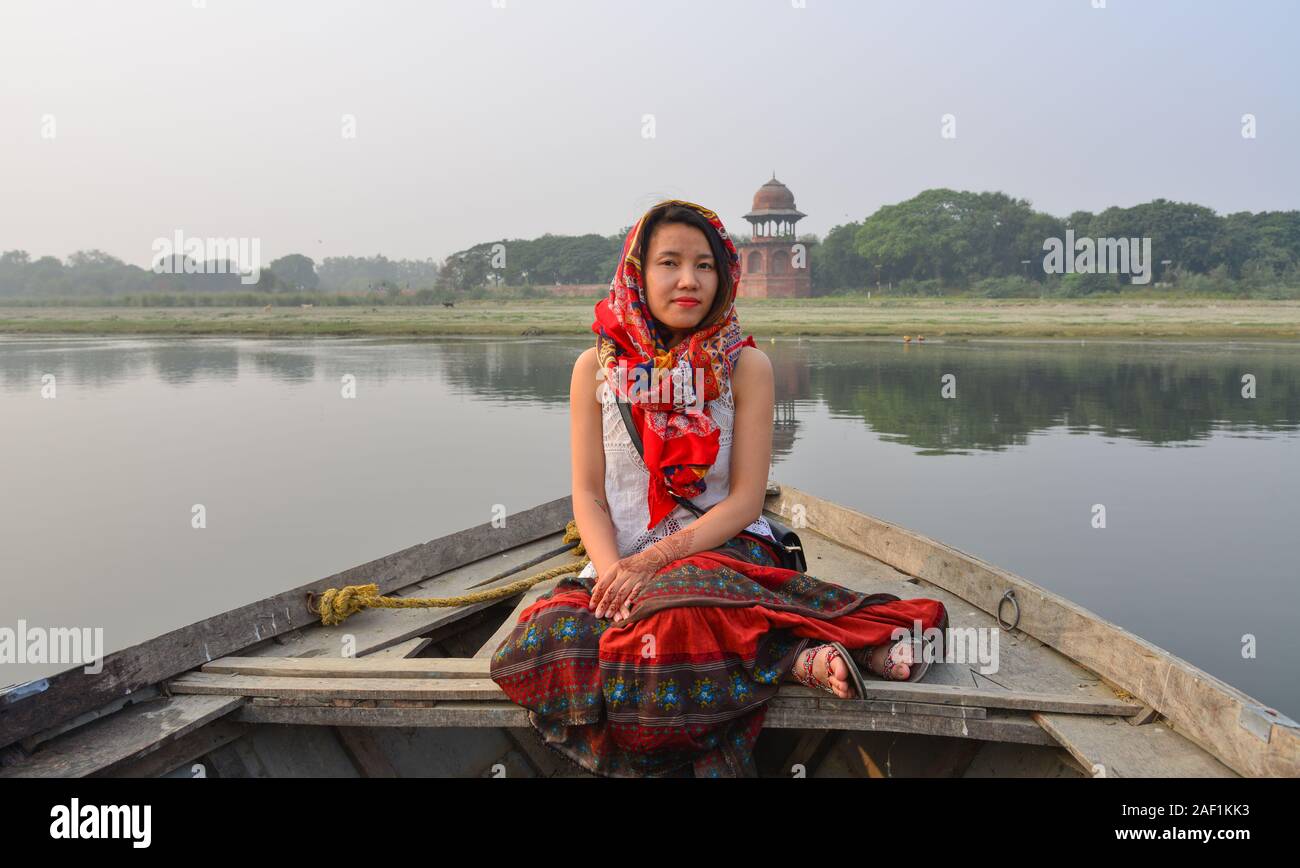 A woman watching sunset over Taj Mahal (Agra, India) from a wooden boat. Stock Photo