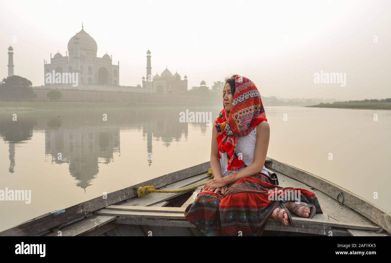 A woman watching sunset over Taj Mahal (Agra, India) from a wooden boat. Stock Photo