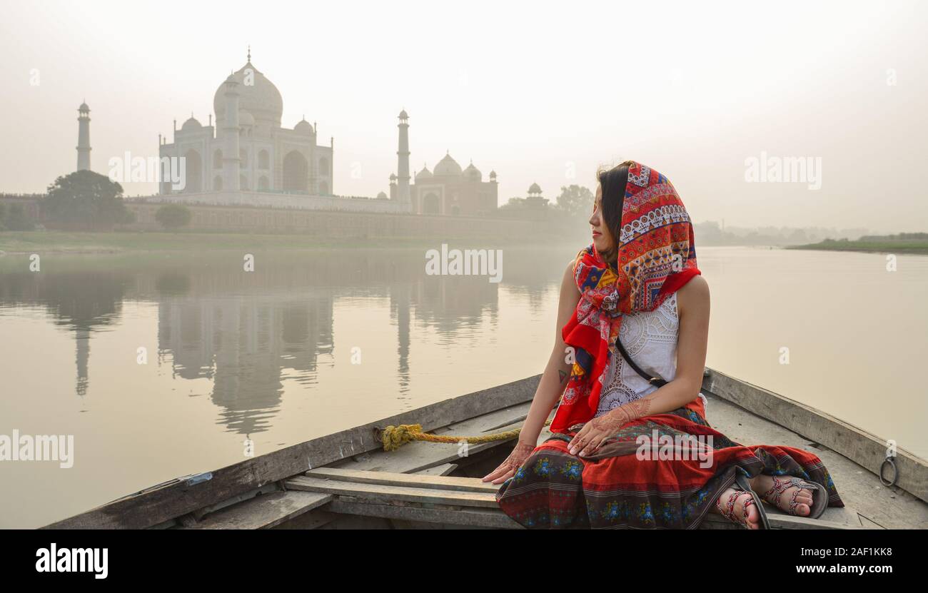 A woman watching sunset over Taj Mahal (Agra, India) from a wooden boat. Stock Photo