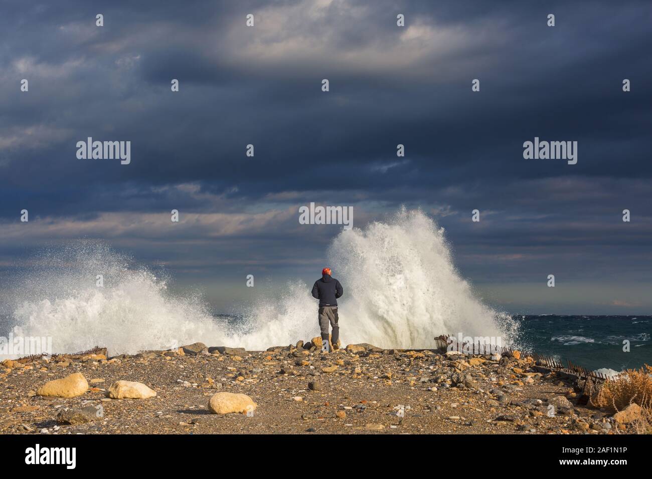 Man standing against the sea on a pier with big wave beating with ...