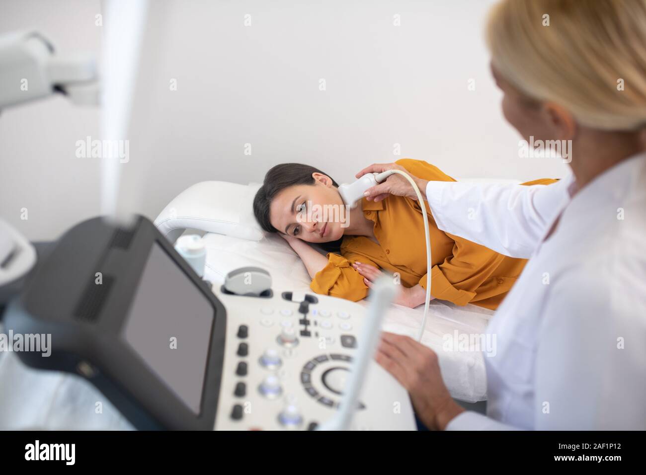 Ultrasound specialist in white robe making lymph node ultrasound test Stock Photo