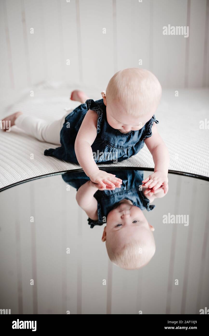 Baby girl looking at reflection in mirror Stock Photo