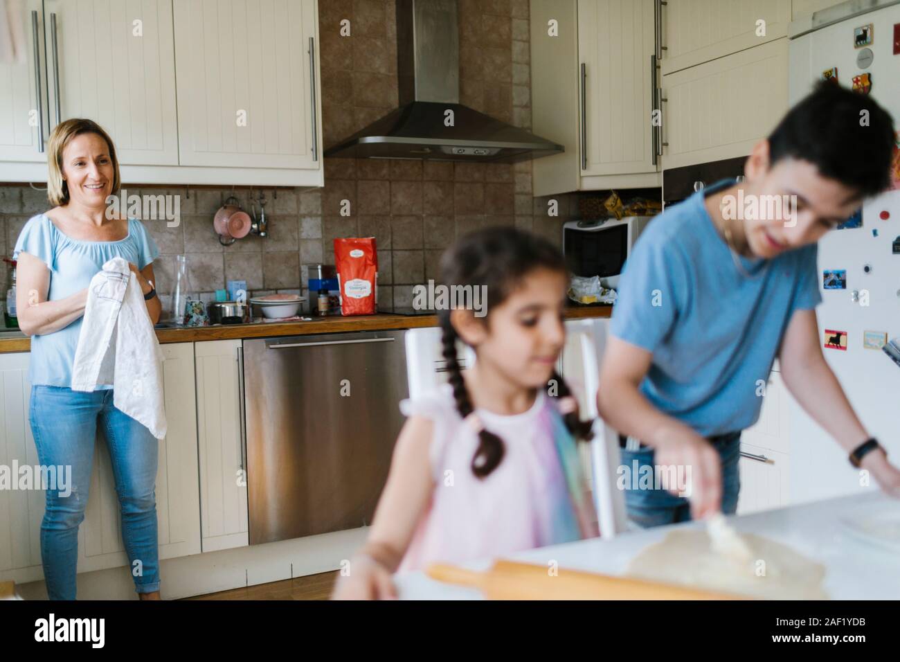 Mother looking at children in kitchen Stock Photo