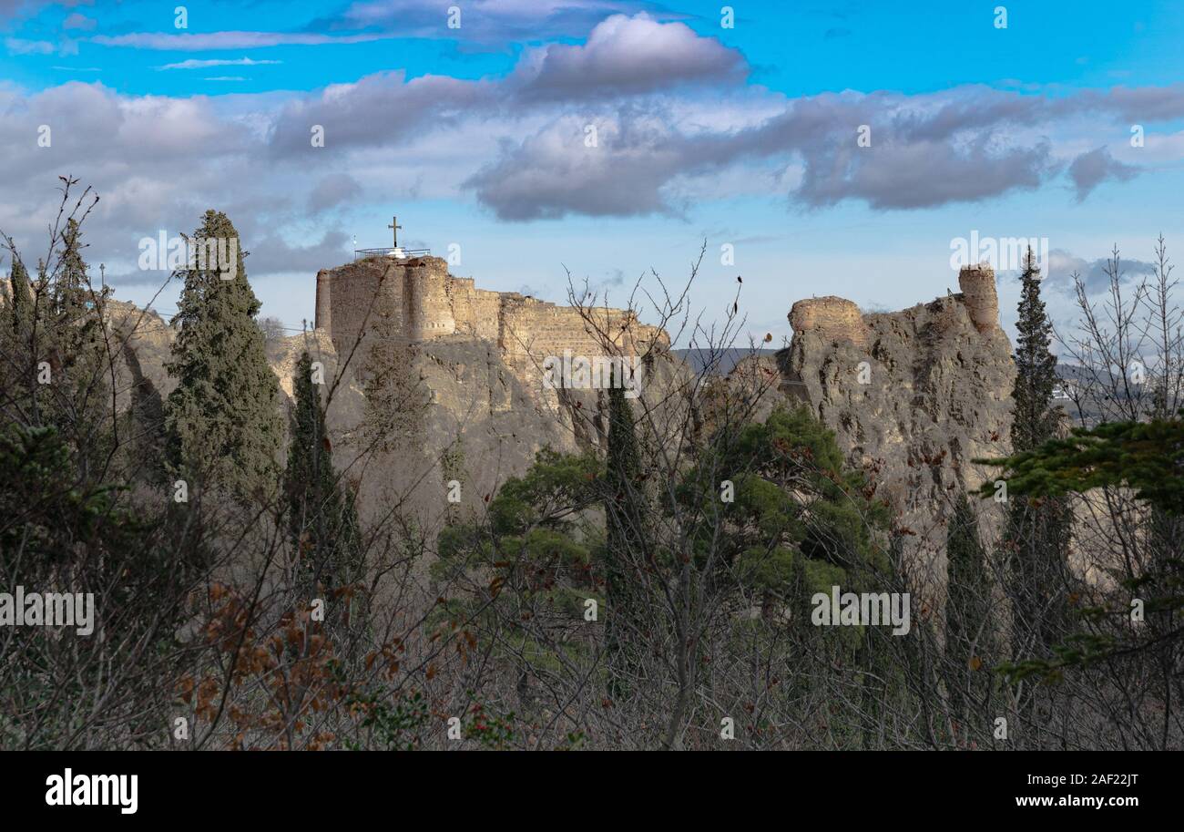 The ruins of Narikala fortress against the background of a blue transparent sky from the side of the Botanical Garden. Tbilisi. Georgia. Stock Photo