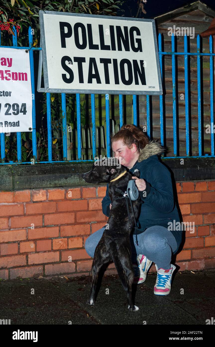 Wirral, UK. 12th December 2019. An early, busy start to voting, as polling stations open across the UK in the general election, the first to be held in December since 1923. Here, a voter has brought their dog to the polling station.  Credit: Paul Warburton/Alamy Live News Stock Photo