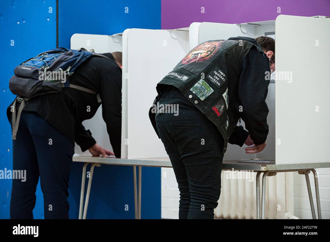 Wirral, UK. 12th December 2019. An early, busy start to voting, as polling stations open across the UK in the general election, the first to be held in December since 1923. Pictured are two voters filling in their ballot paper.  Credit: Paul Warburton/Alamy Live News Stock Photo
