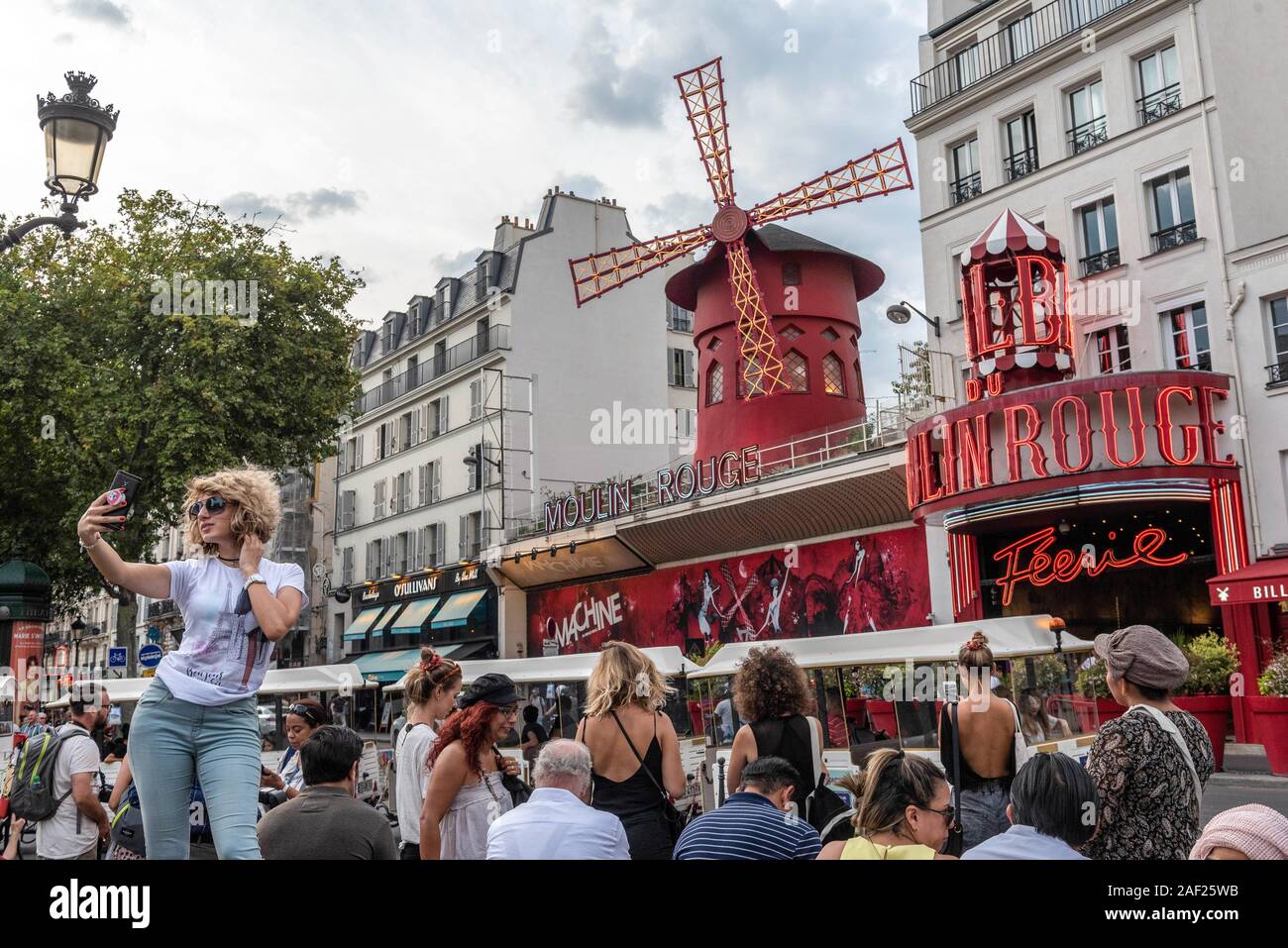 Paris (France): atmosphere in the district of Montmartre, tourists taking pictures in front of the Moulin Rouge cabaret. Young woman taking a selfie Stock Photo