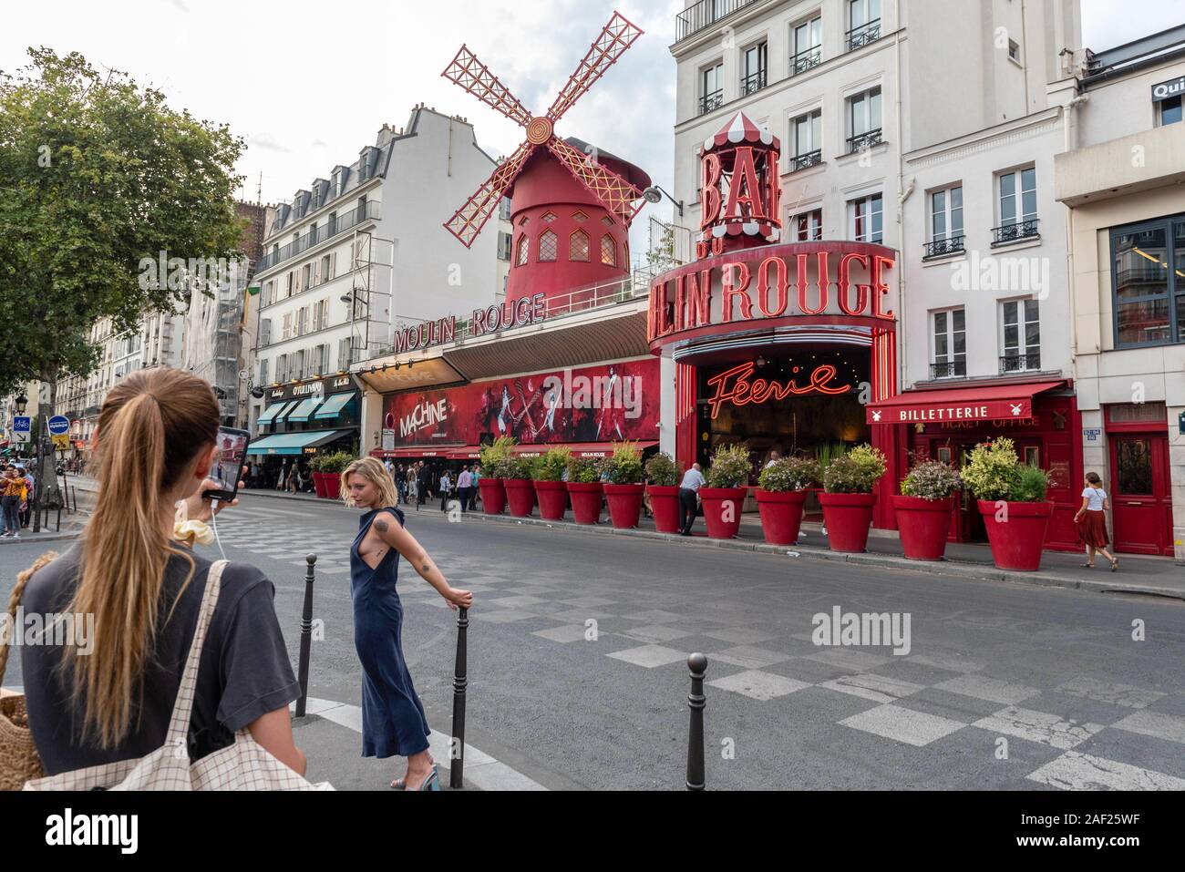 Paris (France): atmosphere in the district of Montmartre, tourists taking pictures in front of the Moulin Rouge cabaret. Stock Photo