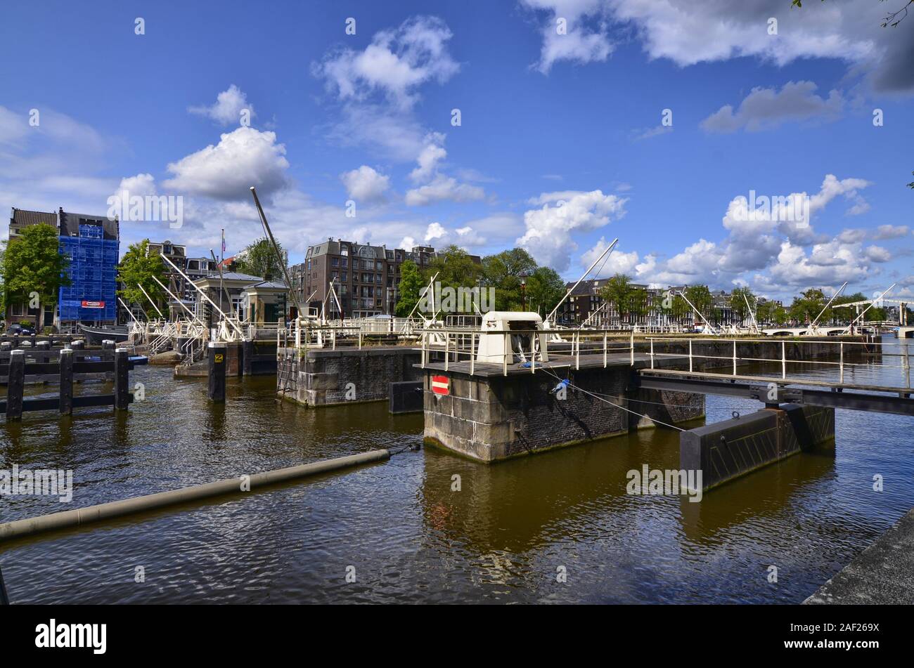 Amsterdam, Holland, August 2019. The dam on the Amstel river. Metal parts painted in white. Blue sky with white clouds. Stock Photo