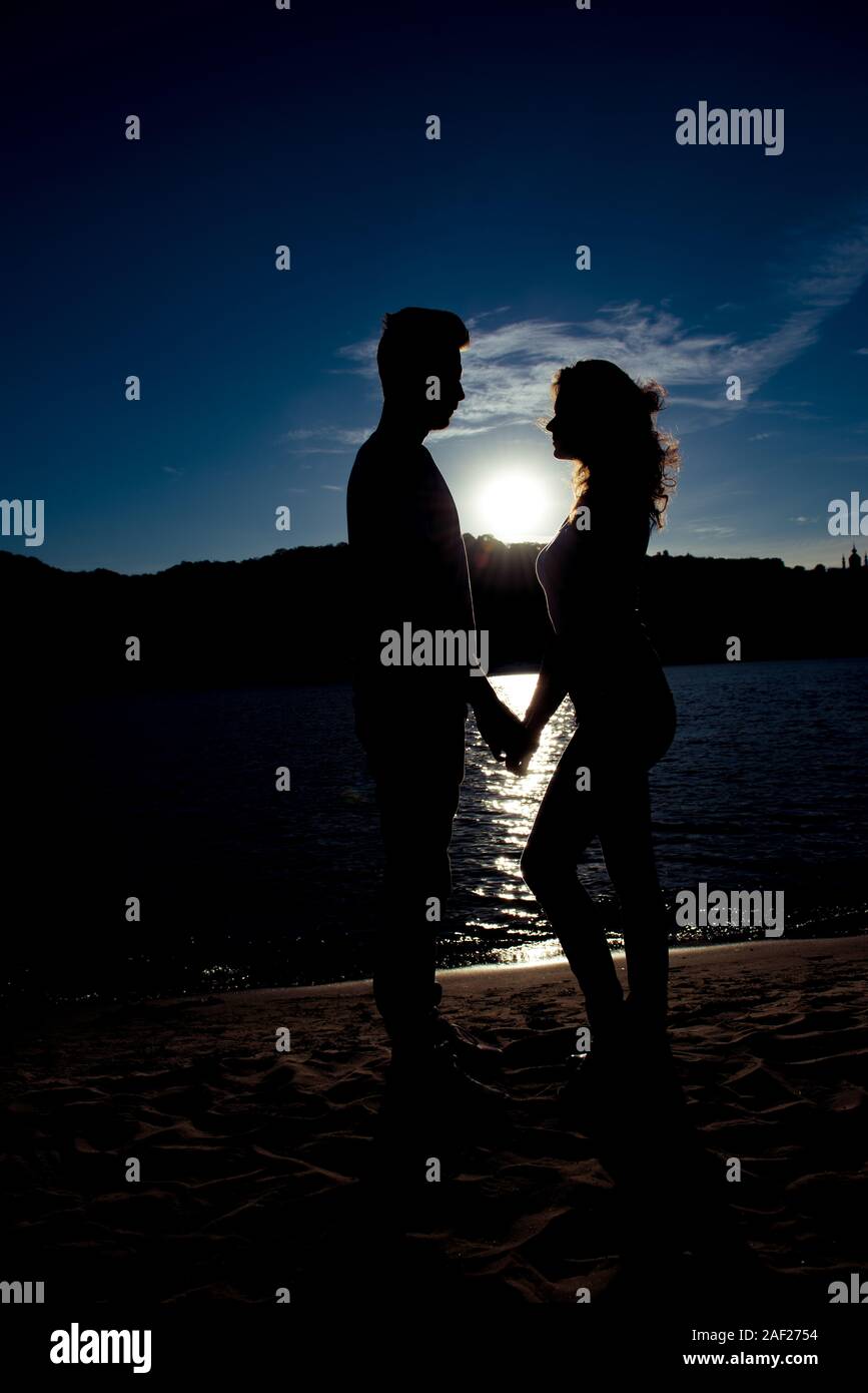 Silhouette of romantic man and woman holding hands on the sunset Stock ...
