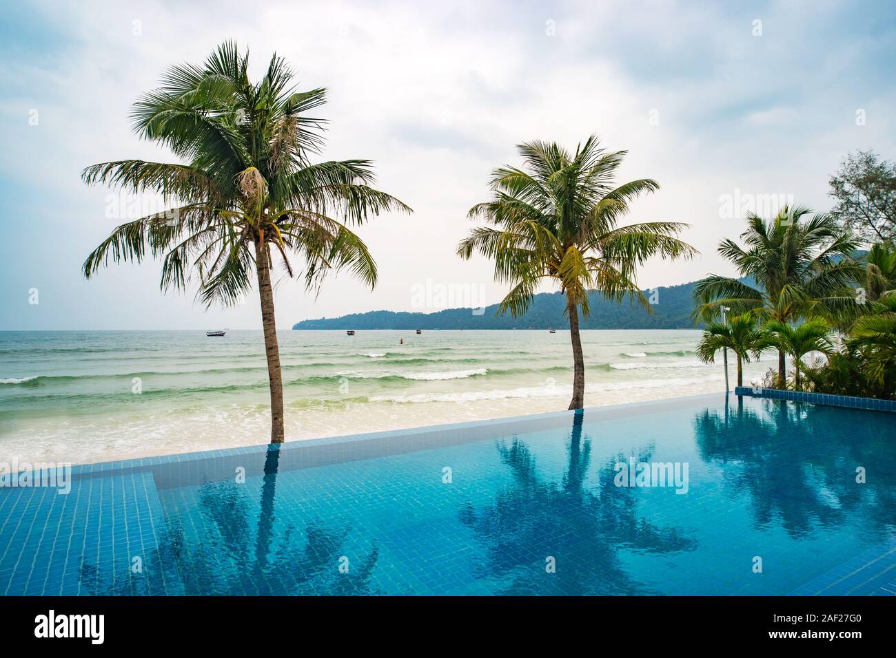 Coconut palms are reflecting in the water. Swimming pool on the background of sea. Beautiful luxury holiday on a tropical island. Outdoor swimming poo Stock Photo