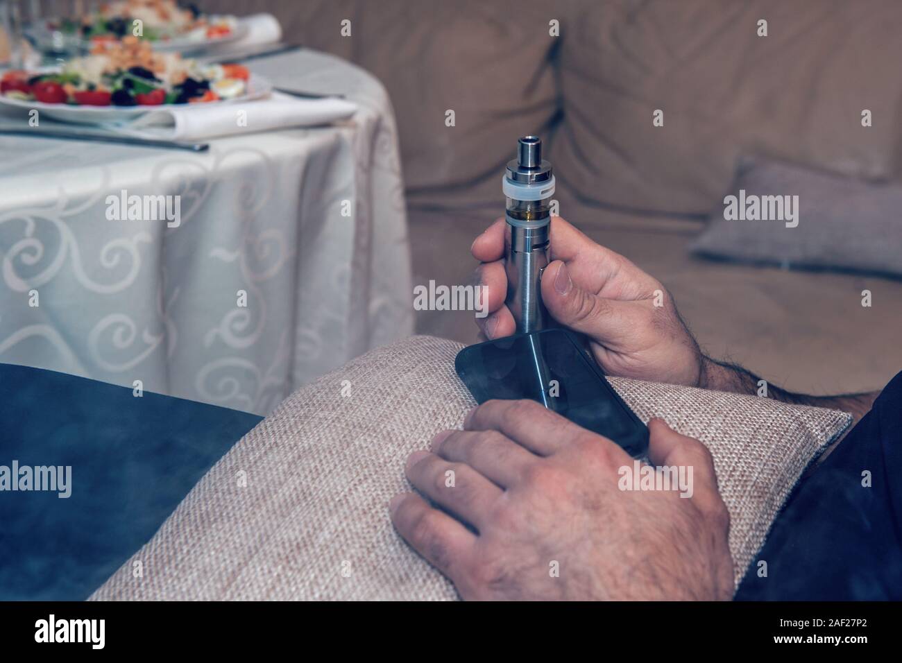 Ban electronic cigarettes. A man holds an electronic cigarette. Harm to health, replacement of