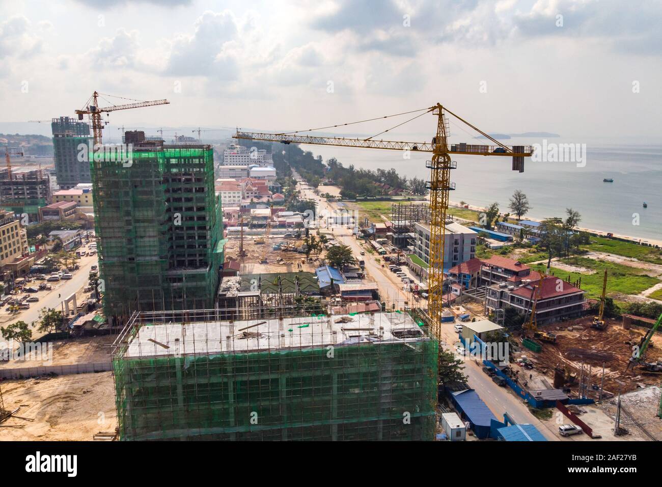 Construction high-rise building by crane in city near sea. construction of expensive hotels in resort town of Sihanoukville, Cambodia. A lot of constr Stock Photo