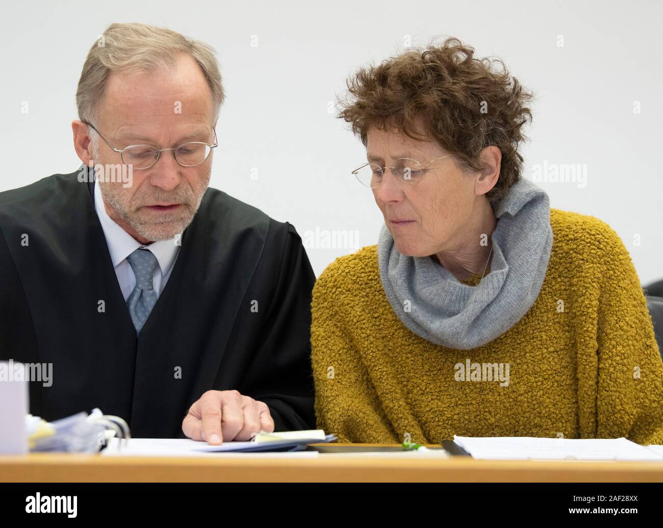 12 December 2019, Hessen, Gießen: Gynaecologist Kristina Hänel sits in the dock in the courtroom and talks to her defender Karlheinhz Merkel. The regional court concerns itself again with the question whether the lady doctor offended against the controversial abortion paragraph 219a. The public prosecutor's office accuses Hänel of having offered abortions as a service on its website and thus violated the law. Photo: Boris Roessler/dpa Stock Photo