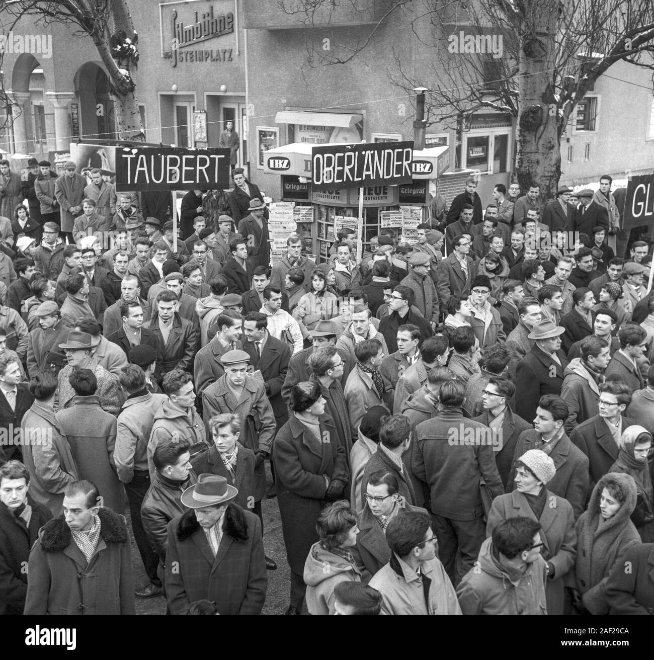 A group in the crowd shows signs with names of former members of the ...