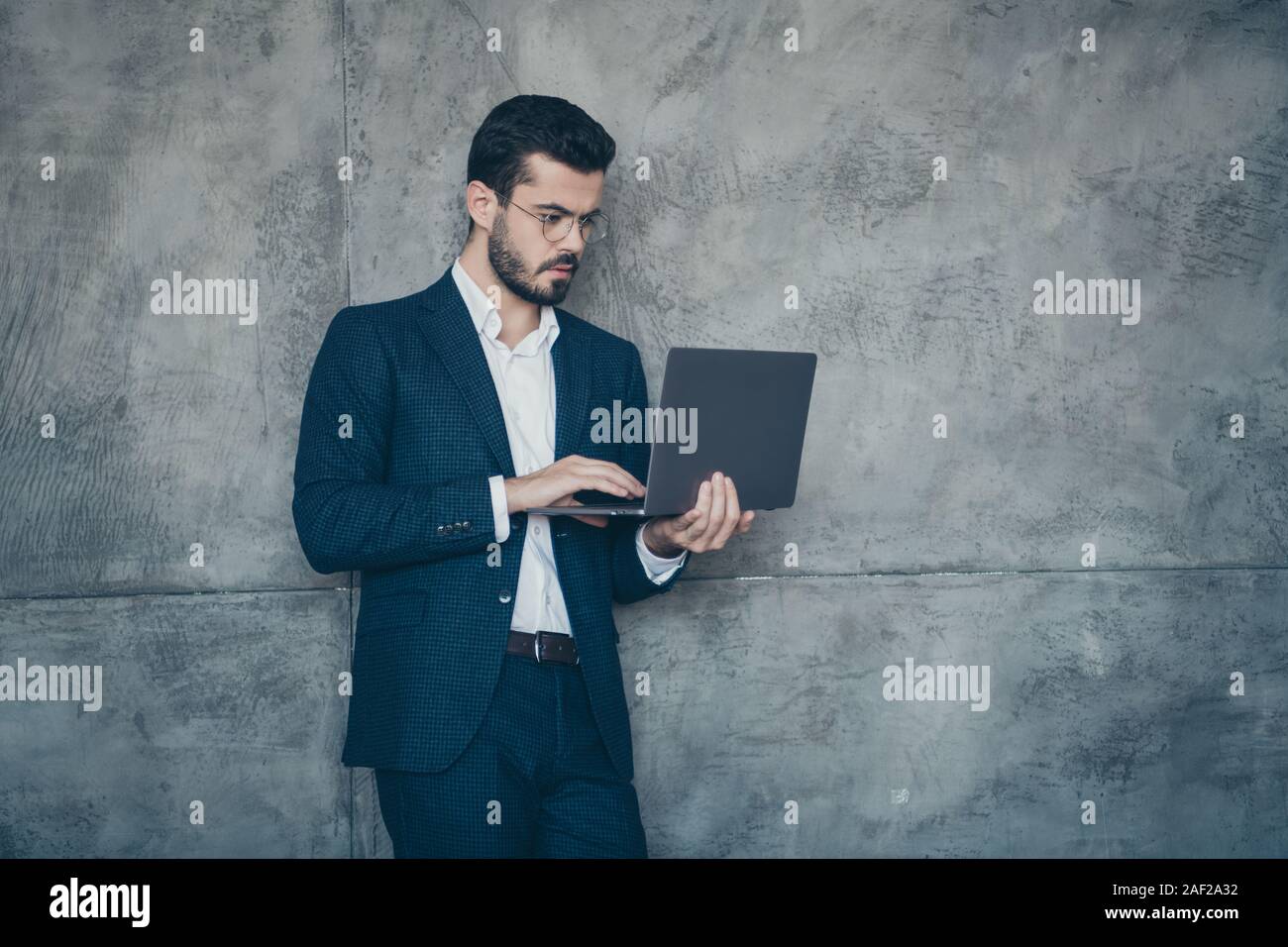 Portrait of his he nice attractive imposing luxurious focused concentrated bearded guy financier wearing jacket using laptop isolated over grey Stock Photo