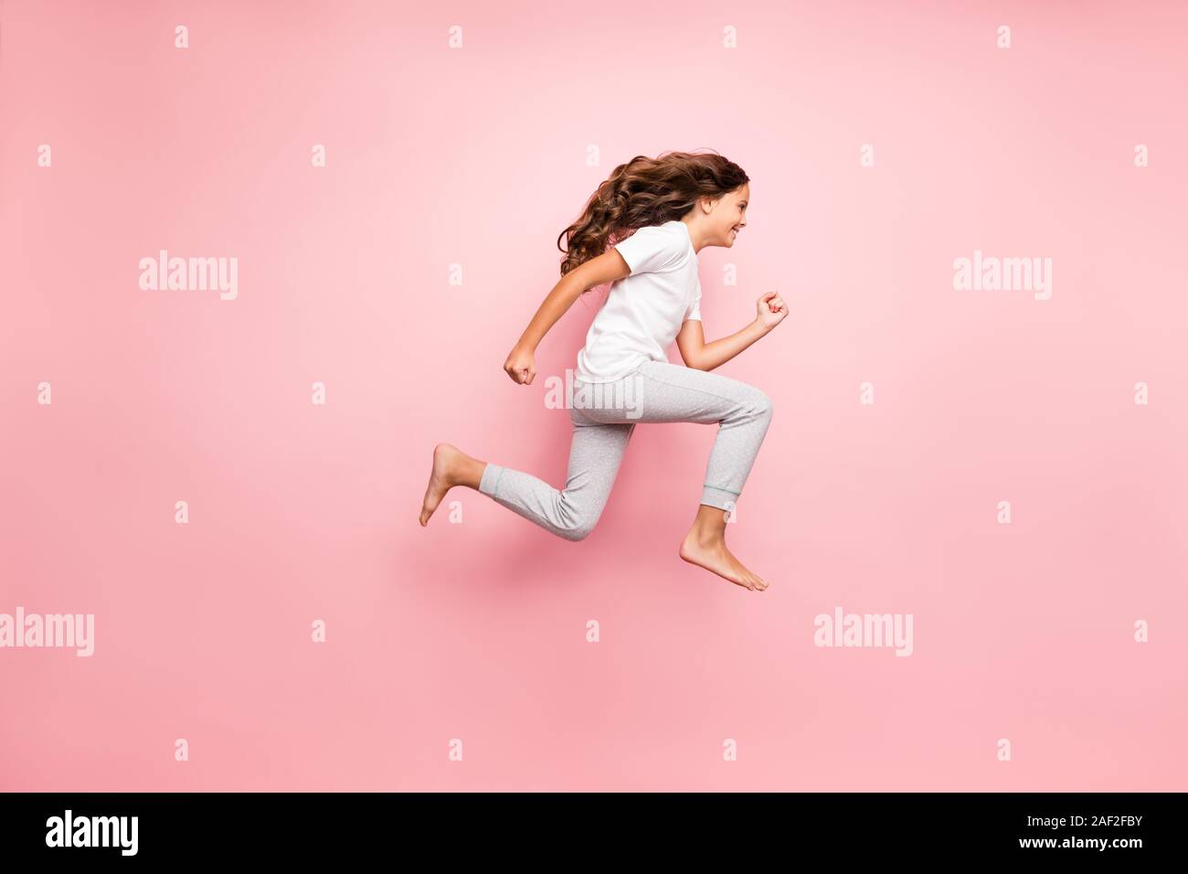 Full length body size side profile photo of cheerful barefoot positive running urgent hurrying preteen wearing t-shirt isolated over pastel color Stock Photo
