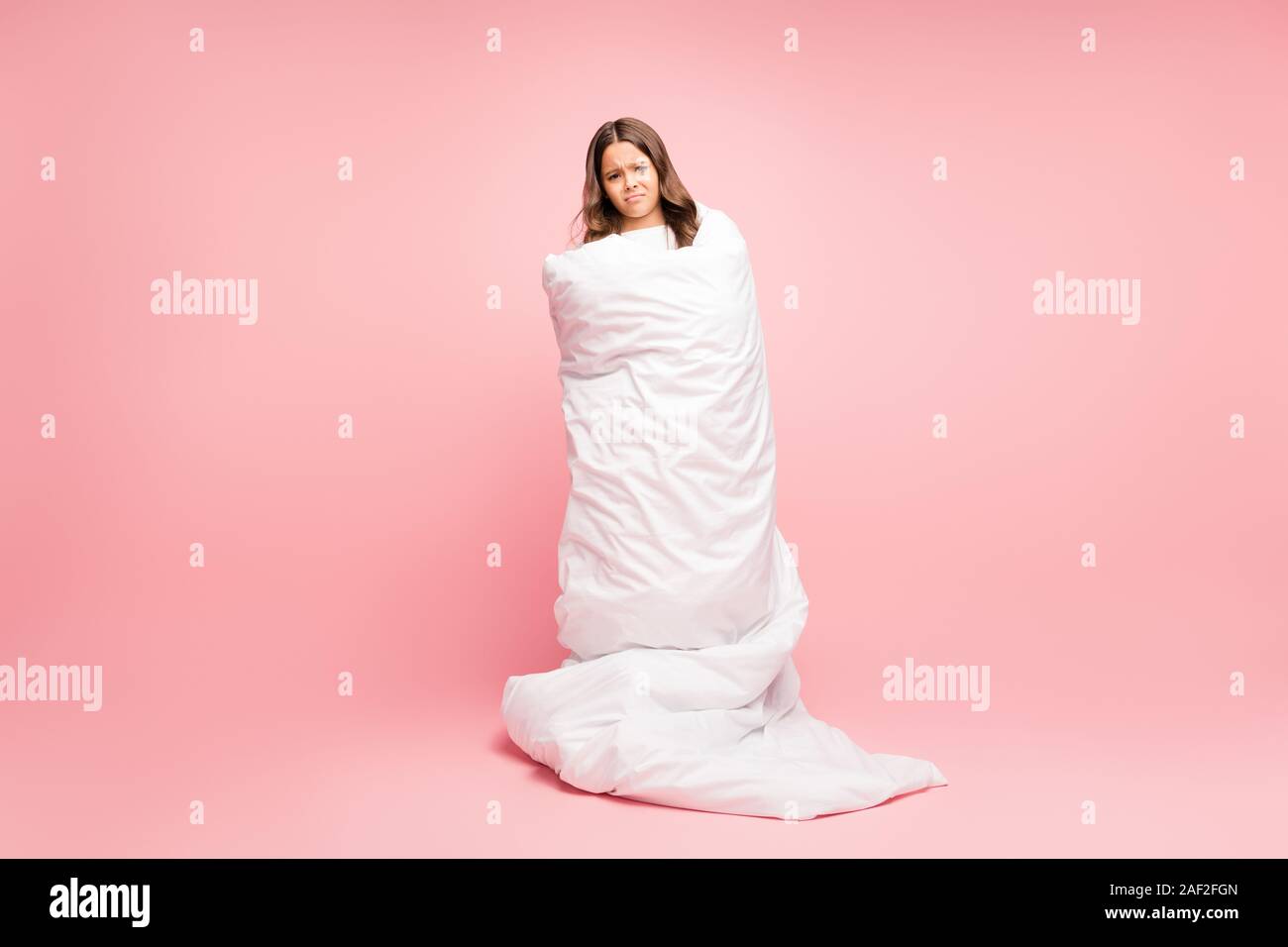 Full length body size view of her she nice attractive cute disobedient sad wavy-haired pre-teen girl wrapped in soft white duvet isolated over pink Stock Photo