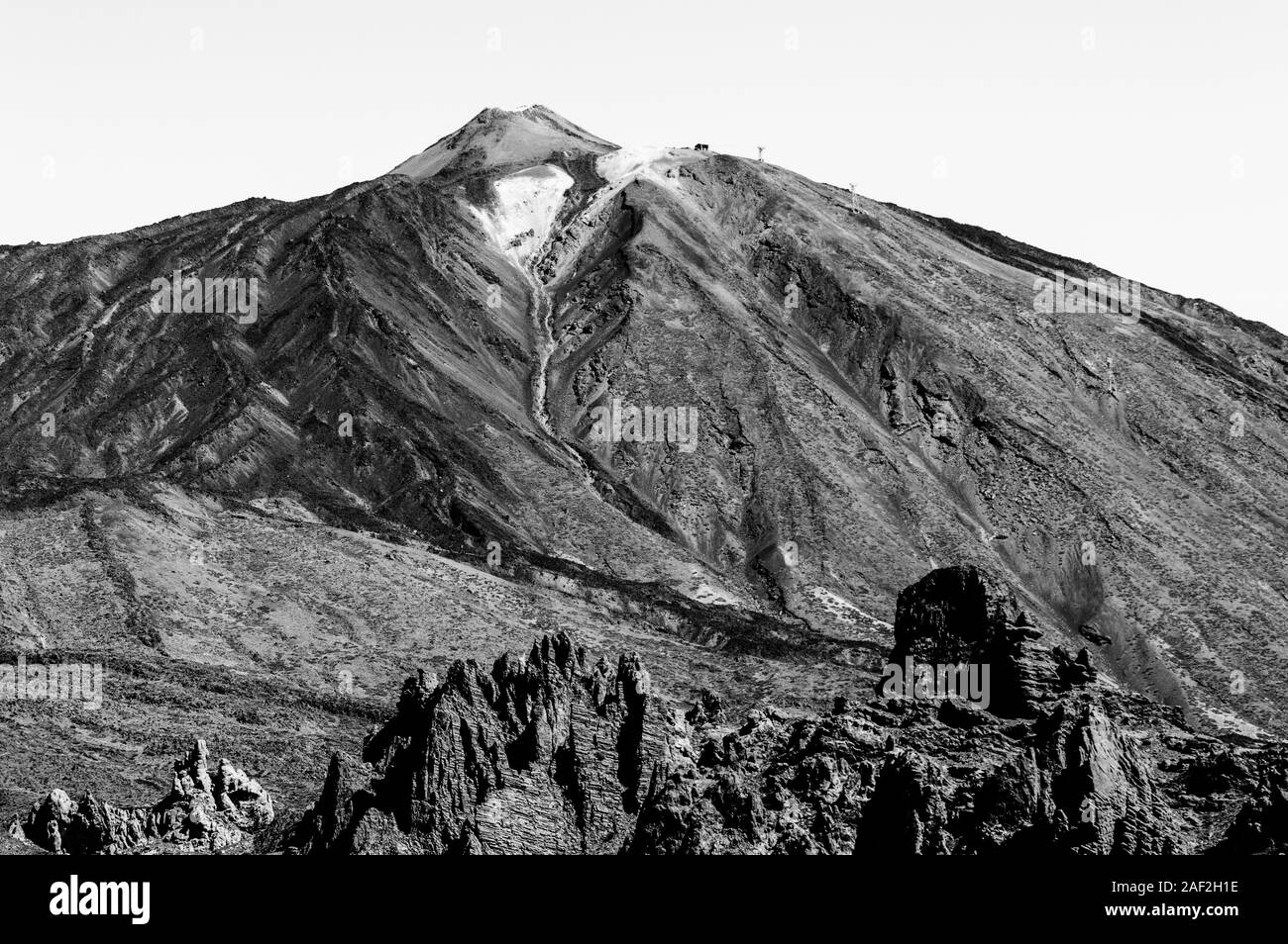 Black And White Shot Of The Highest Peak Behind Formations Of Lava Rocks On A Sunny And Very Clear Day In El Teide National Park. April 13, 2019. Sant Stock Photo