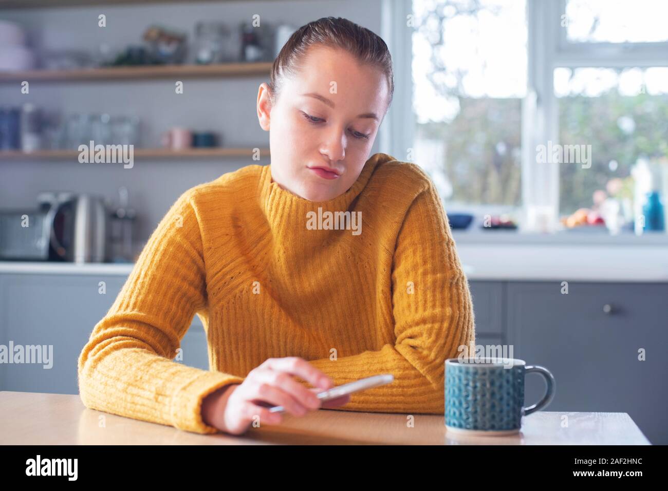 Woman Concerned About Excessive Use Of Social Media Laying Mobile Phone Down On Table Stock Photo