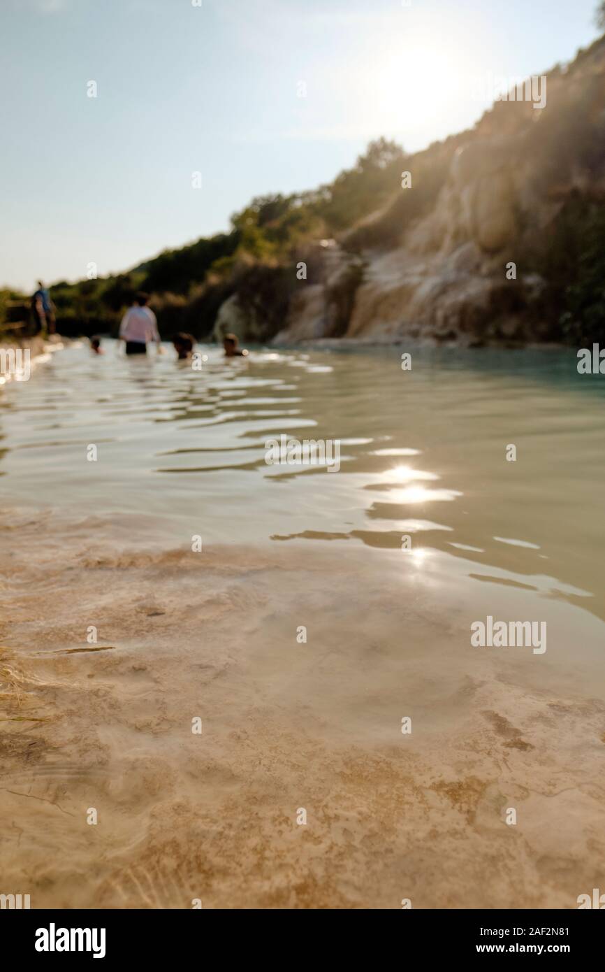 Visitors enjoying the free public thermal water pool of the ancient spa village of Bagno Vignoni, Val d'Orcia, Tuscany Italy EU Stock Photo