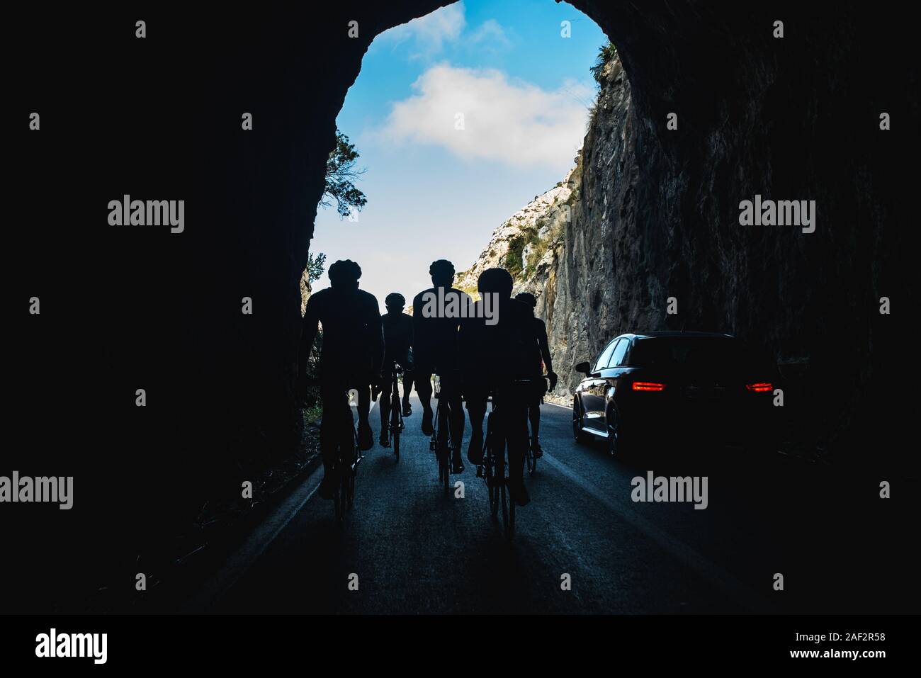Team of road bikers ride in tunnel while training in mountains Stock Photo